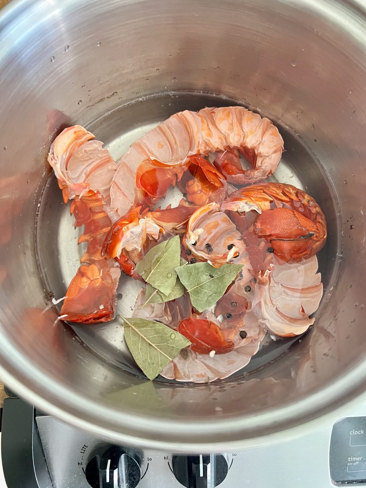 lobster tail shells in water with peppercorn and basil