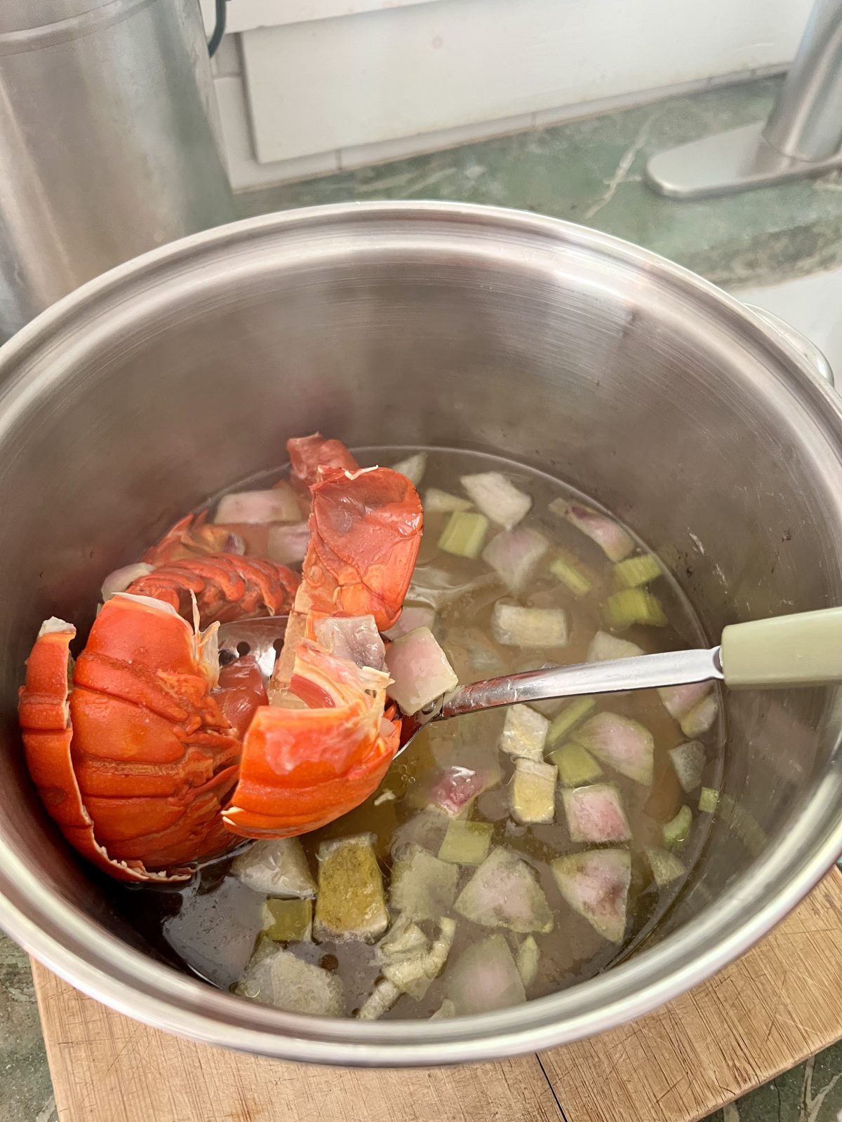 straining spiny lobster shells in a slotted spoon for a homemade lobster stock