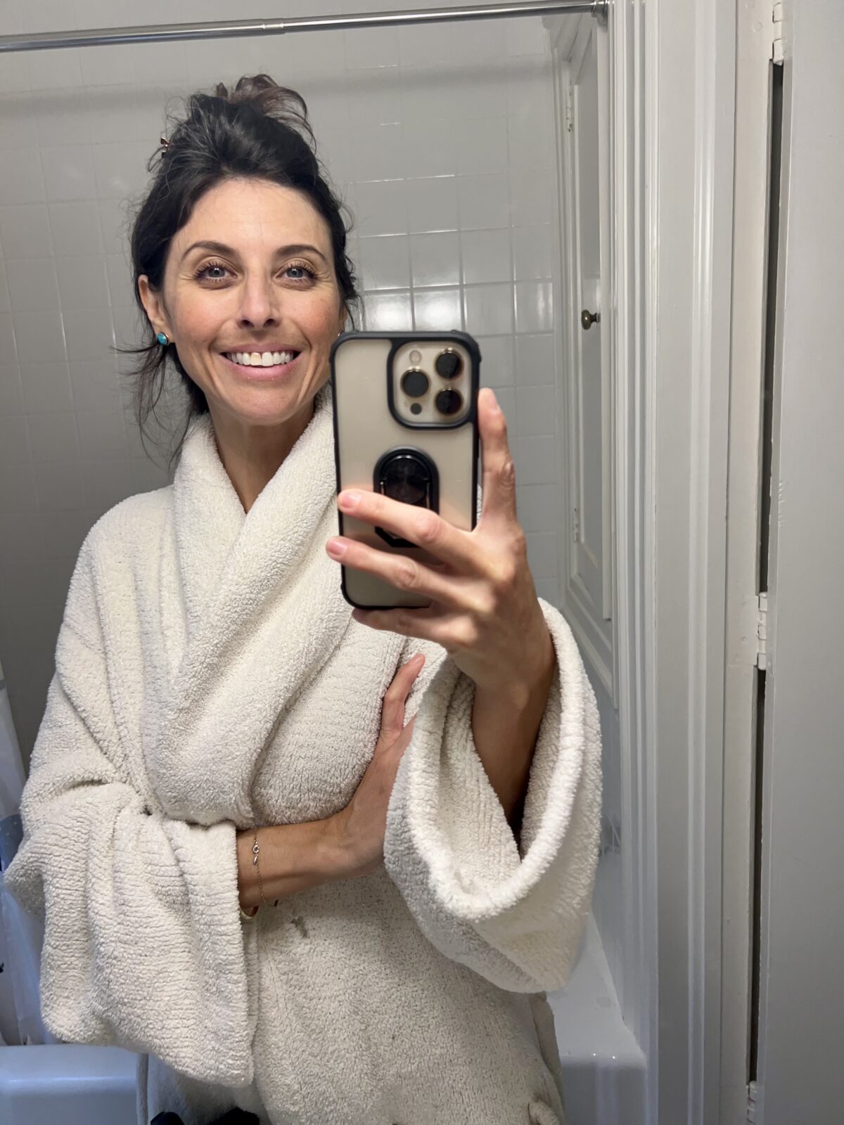 woman in white fluffy robe taking a selfie in the mirror