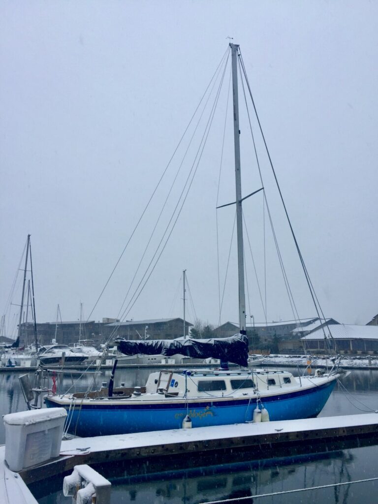 blue sailboat in dock slip in bellingham washington on a snowy day