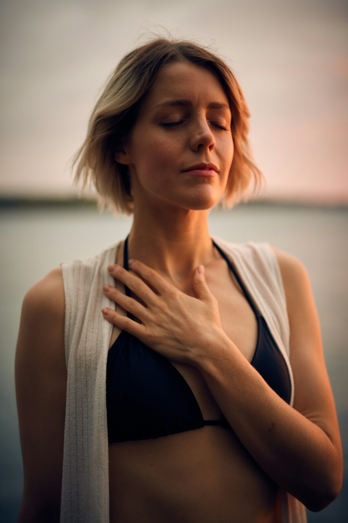 woman-in-white-vest-and-black-bikini-with-hand-on-chest